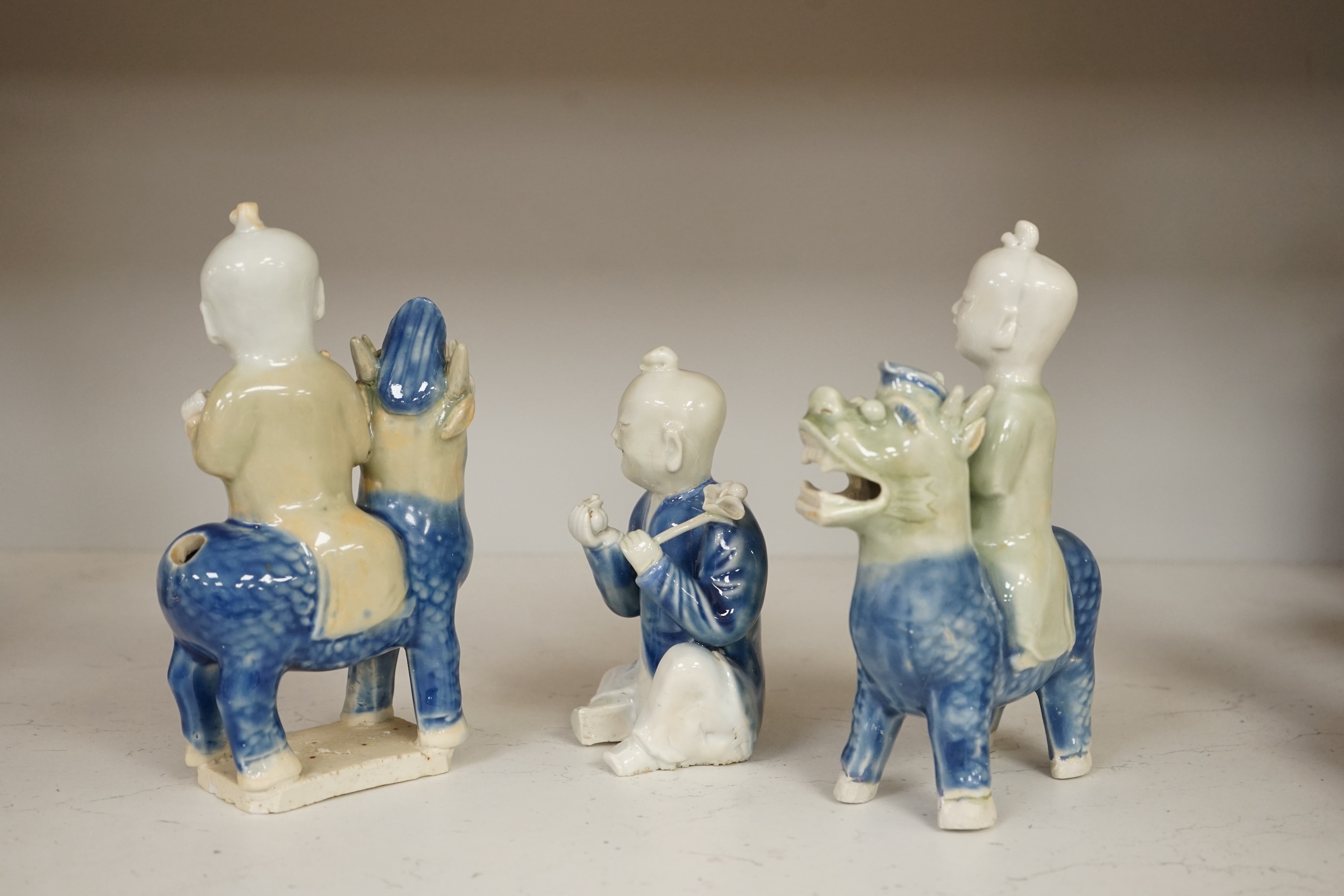 Three Chinese celadon and blue glazed porcelain boy figures, 18th century, largest 20cm high. Condition - fair, all restored